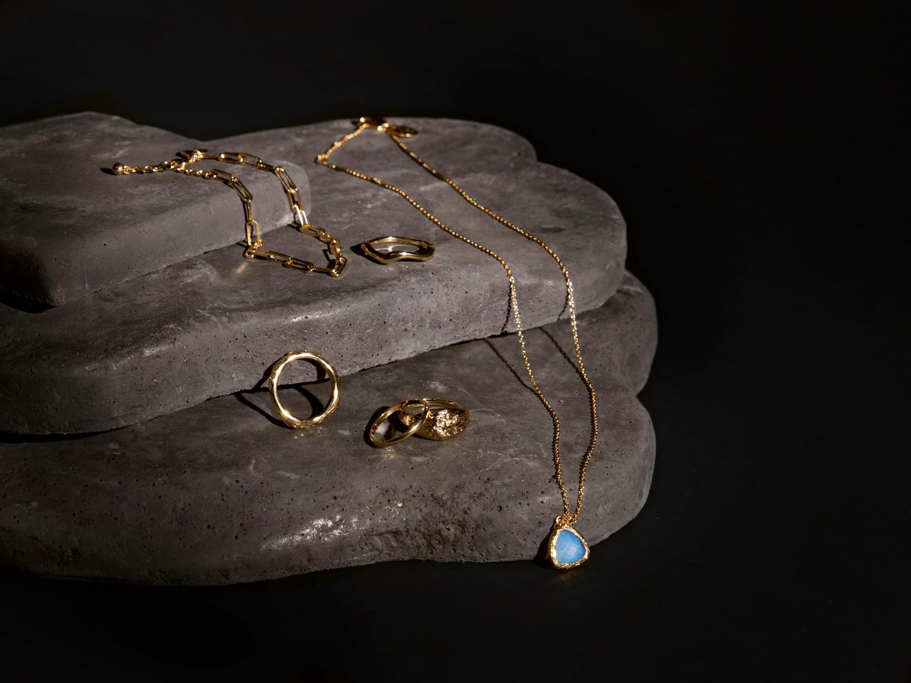 Gold jewellery styled on a warm surface